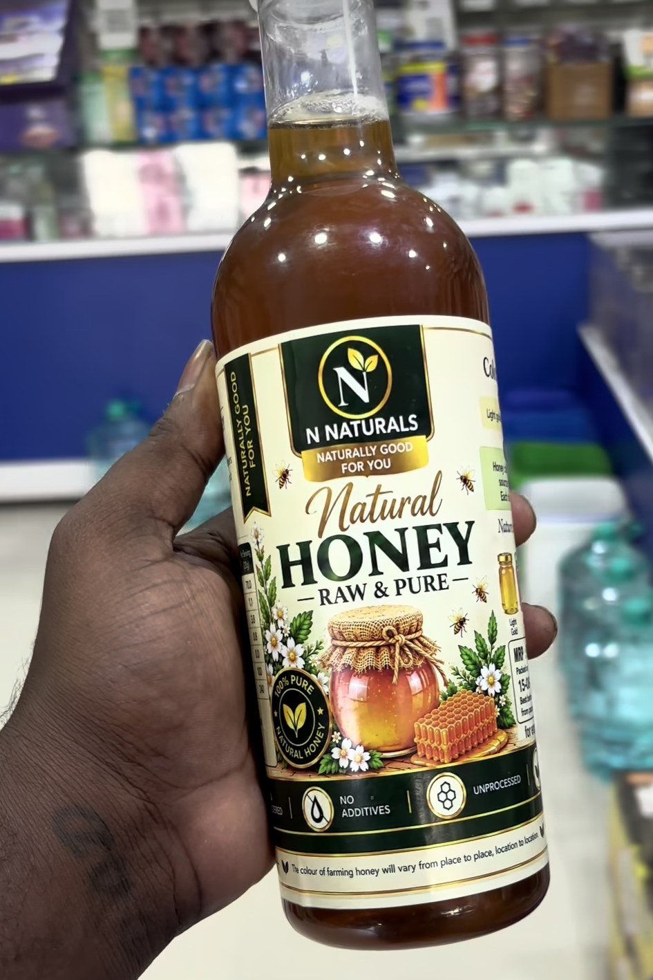 N Naturals Natural Honey, Raw & Pure, in a glass bottle held in a shop